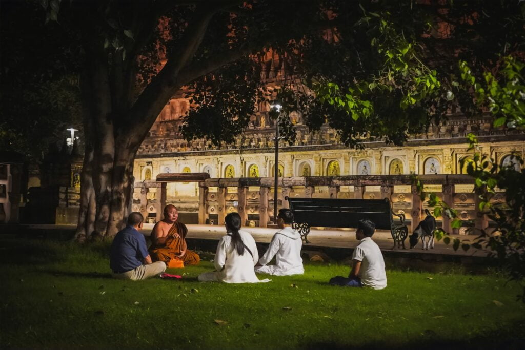 Photo by Nayan Bhalotia a group of people sitting on the grass in front of a building